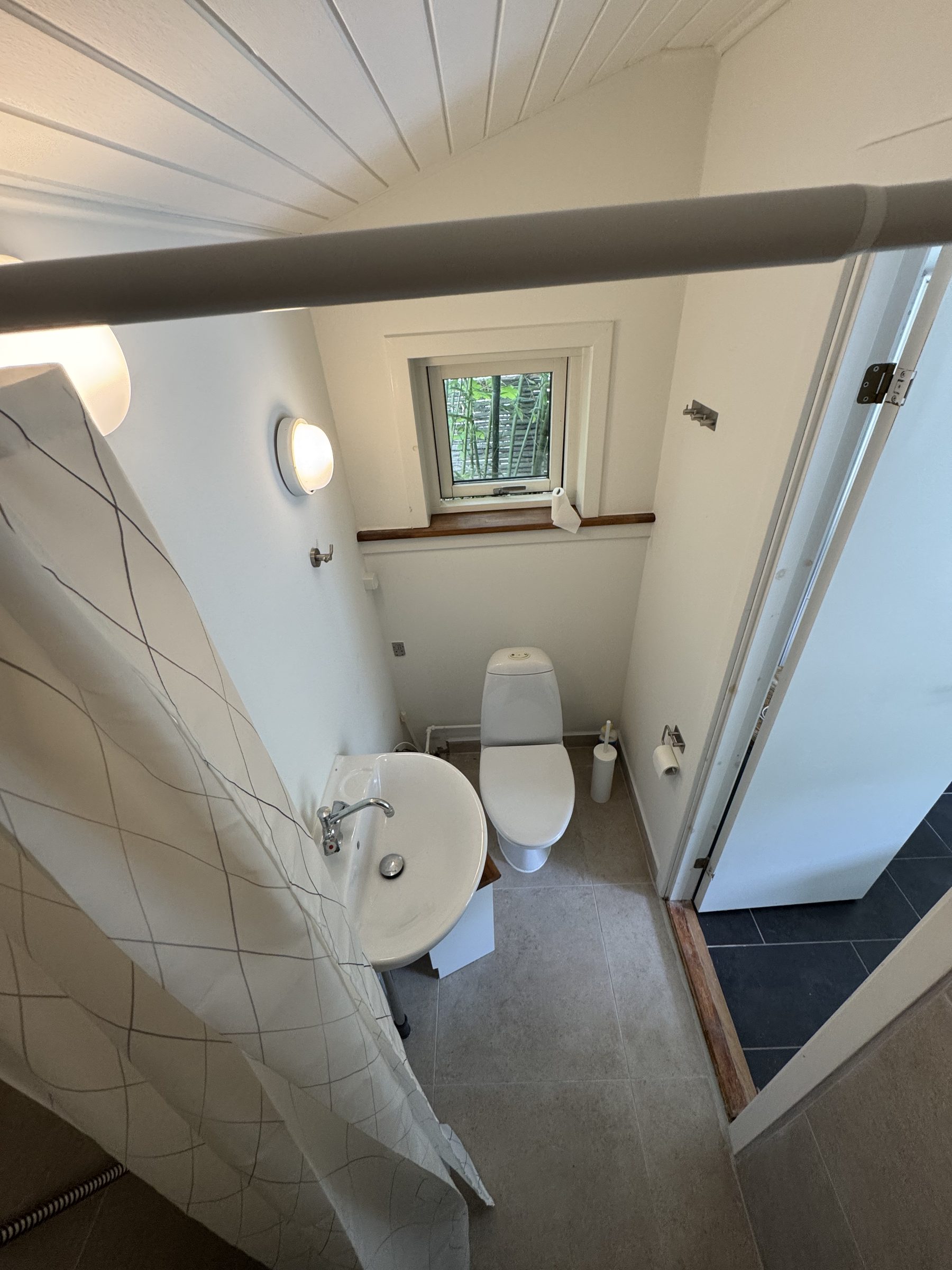 Færdigt toilet med hvide fliser og lille vindue
